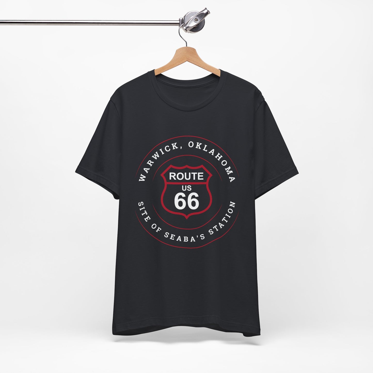 A vintage retro Route 66 unisex jersey tee with Warwick, OK "Site of Seaba's Station" design displayed on a wooden hanger