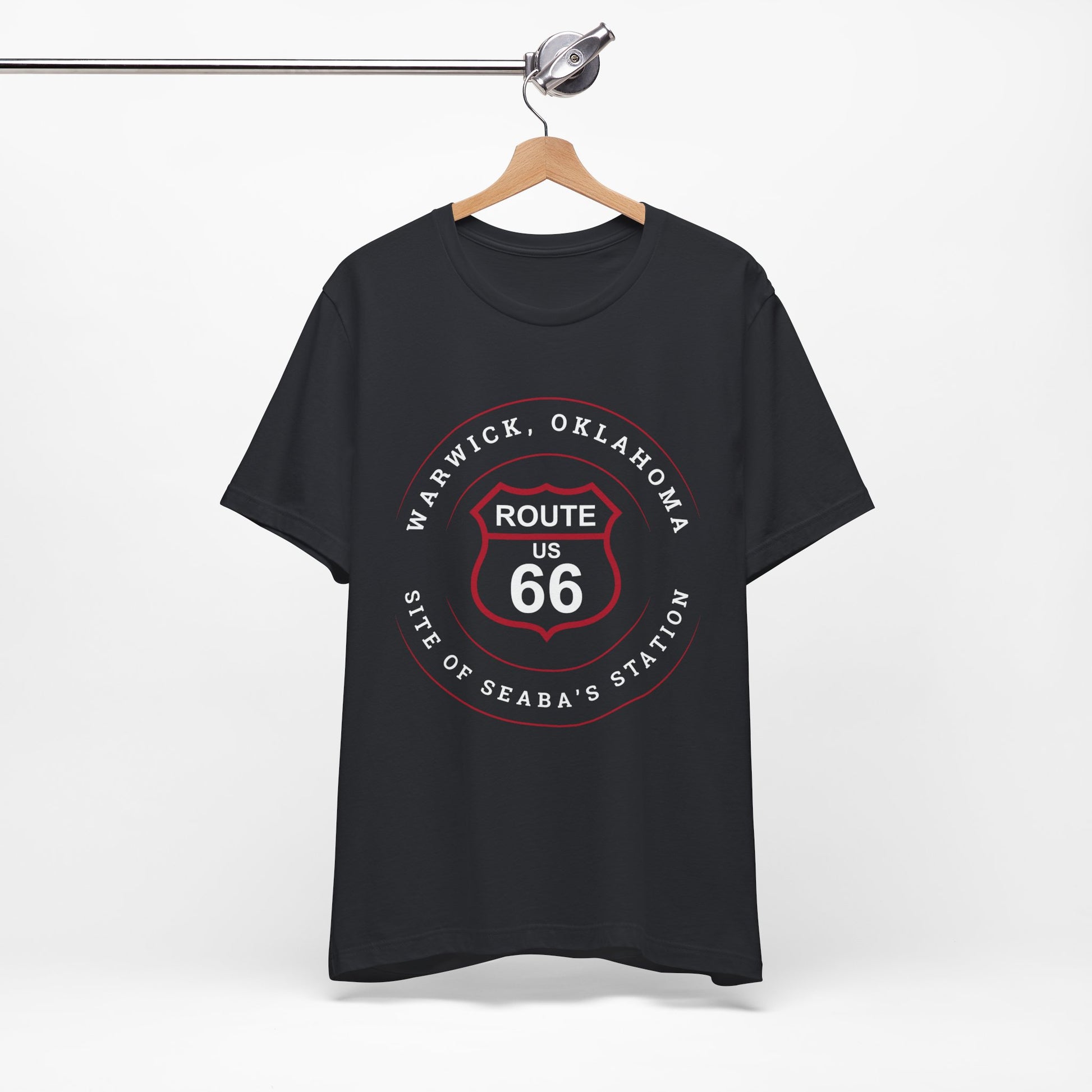 A vintage retro Route 66 unisex jersey tee with Warwick, OK "Site of Seaba's Station" design displayed on a wooden hanger
