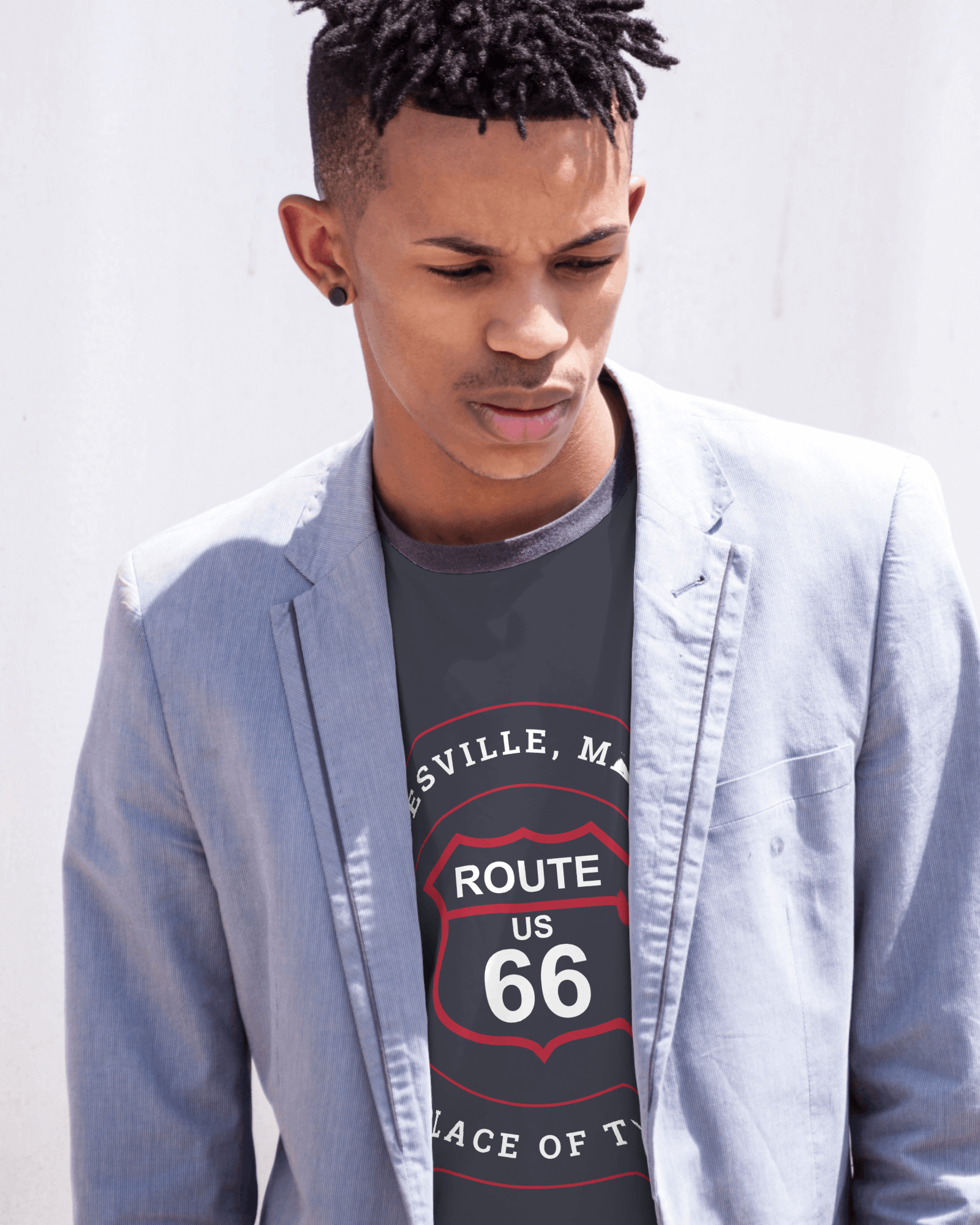 Male model wearing an aqua blazer and a heather true royal retro Route 66 unisex jersey tee with a Waynesville, MO: "Birthplace of the Byway" design