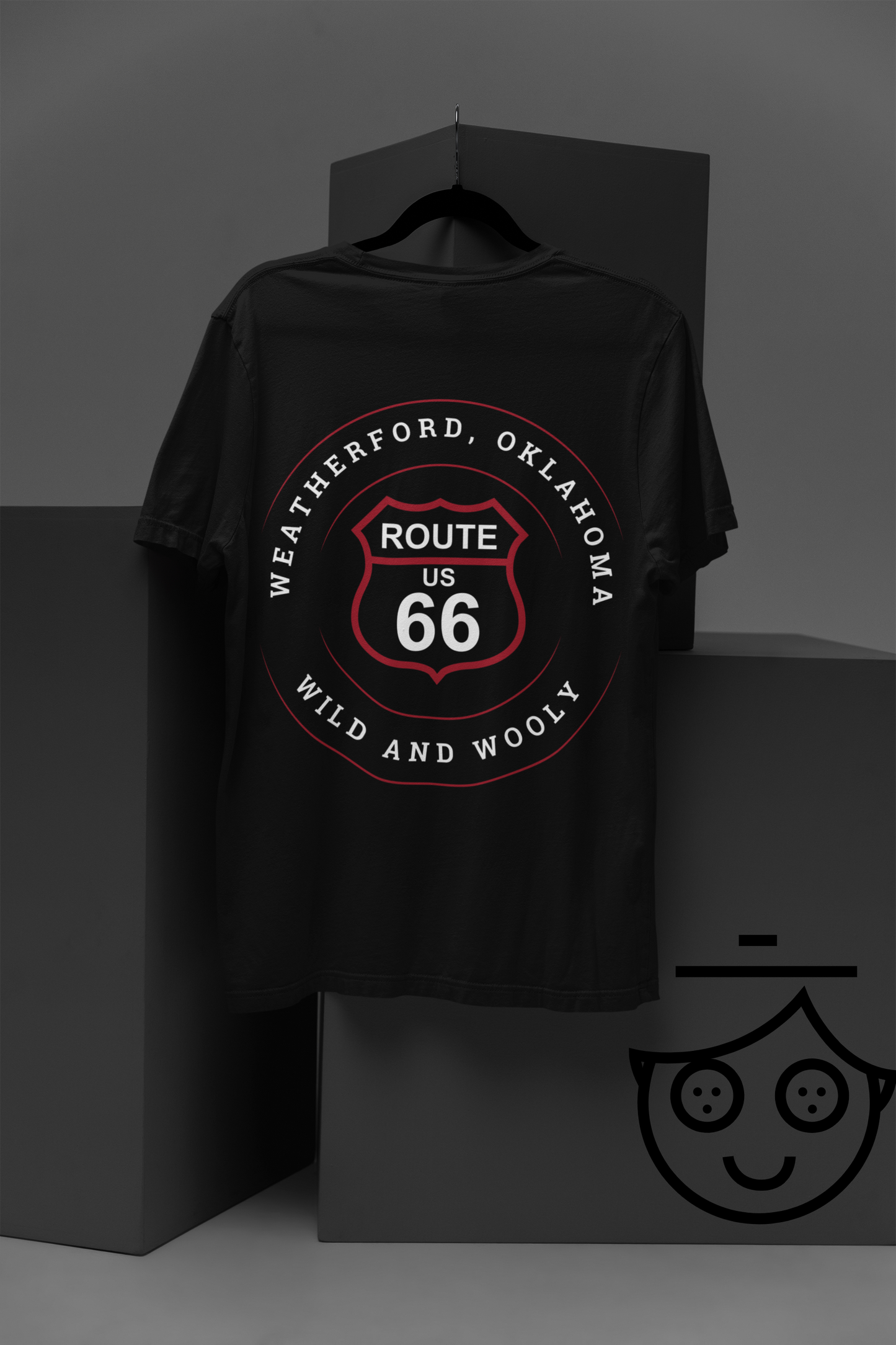 A hanging black retro Route 66 unisex jersey tee with Weatherford, OK "Wild and Wooly" design against grey boxes with lively graphics