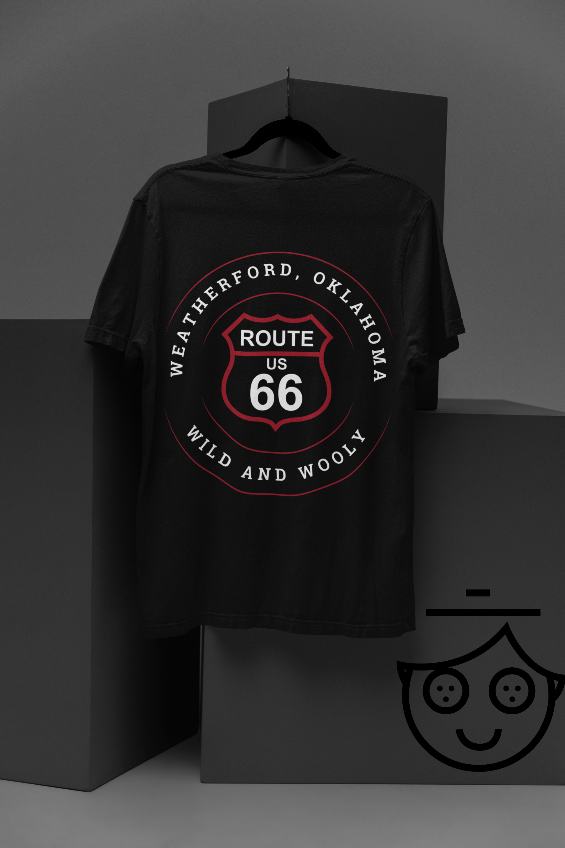 A hanging black retro Route 66 unisex jersey tee with Weatherford, OK "Wild and Wooly" design against grey boxes with lively graphics