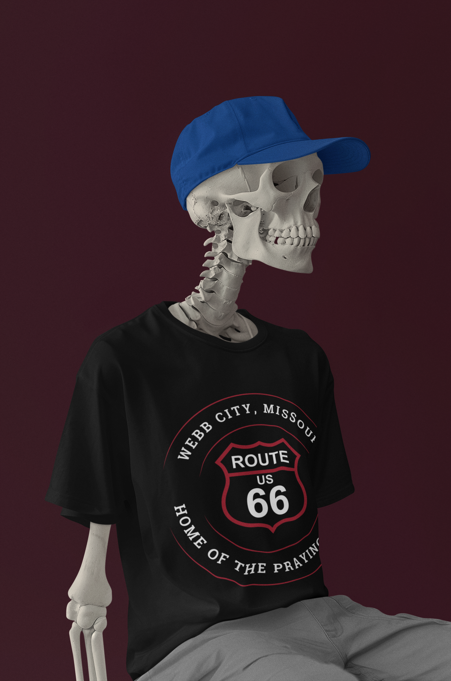 Skeleton model wearing a blue hat and a black retro Route 66 unisex jersey tee with Webb City, MO "Home of the Praying Hands" design
