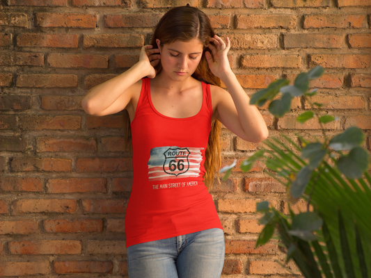 Woman wearing a red Route 66 racerback tank with a watercolor American flag design, standing against a rustic brick wall for a casual summer look